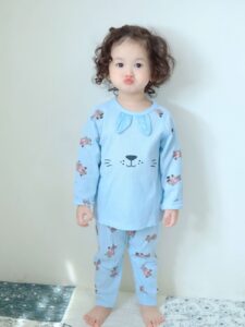 Toddler standing in blue bamboo pajamas with animal print at home