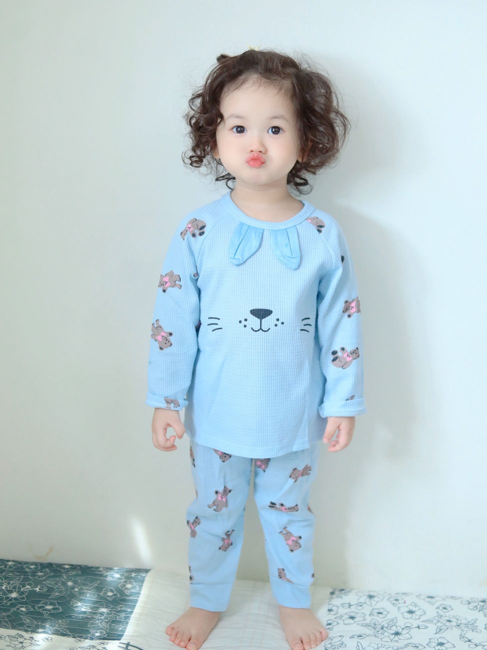 Toddler standing in blue bamboo pajamas with animal print at home