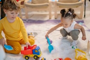 Toddlers playing with indoor toddler activities toys on a rug