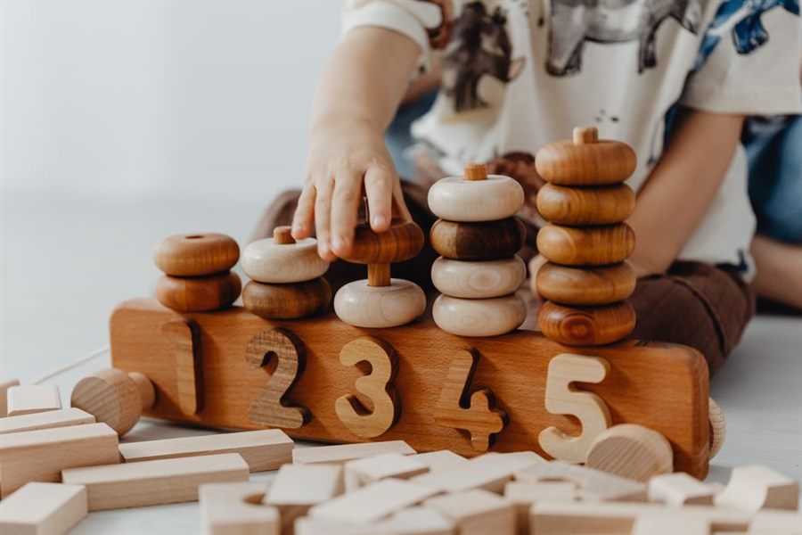 Toddler playing with wooden Montessori stacking toys and number blocks