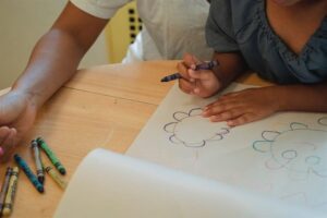 Child coloring with crayons on paper