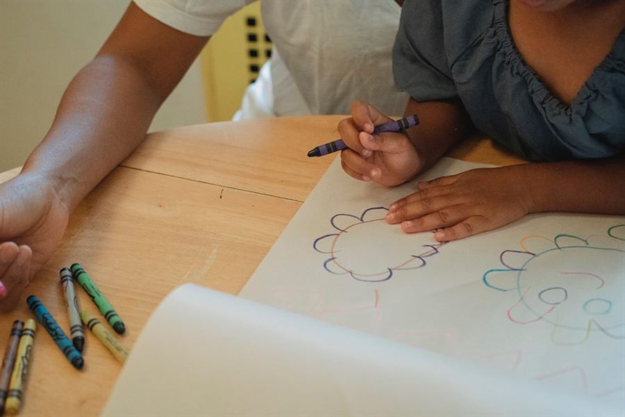 Child coloring with crayons on paper