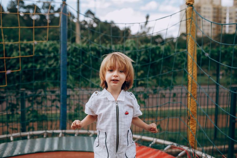 Young child jumping on an outdoor trampoline with safety net