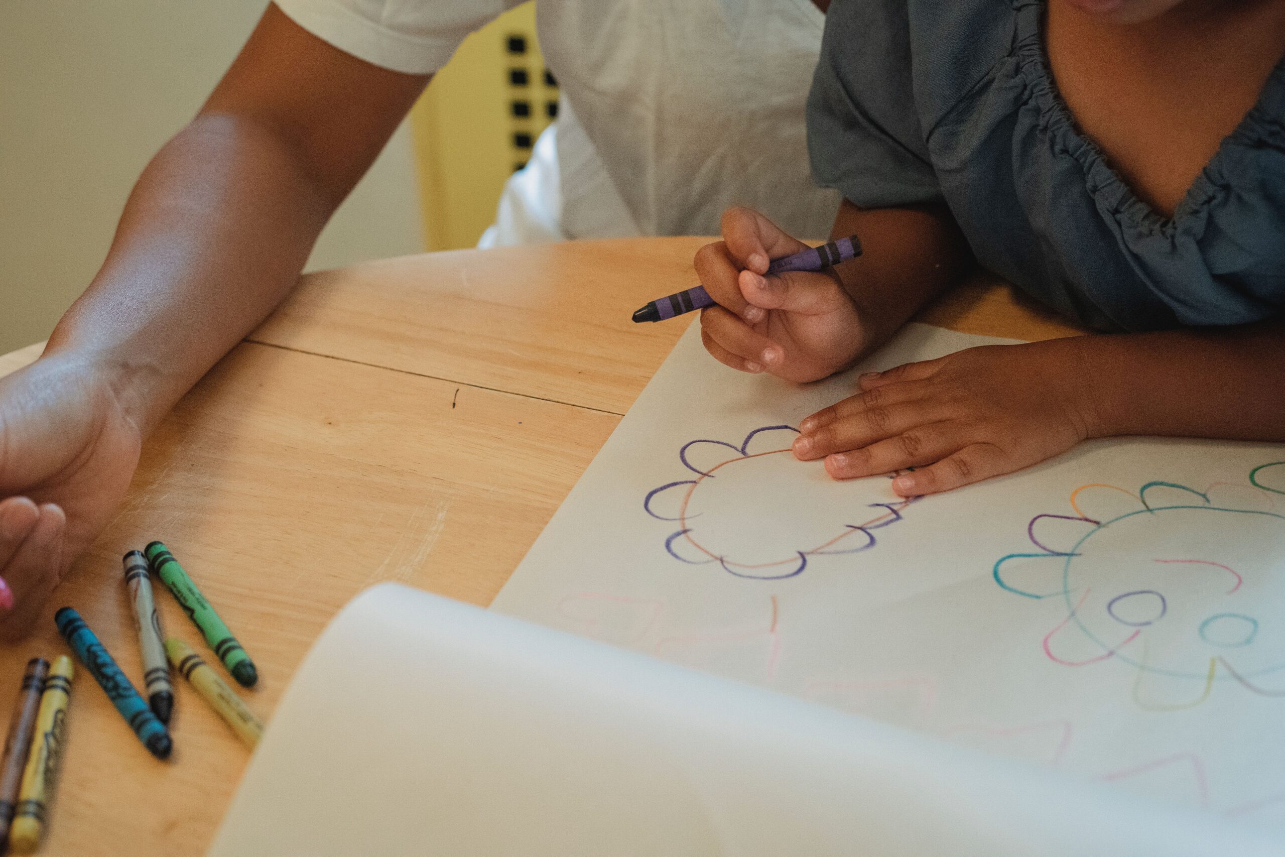 Art supplies for toddlers: a child drawing with wax crayons at a table