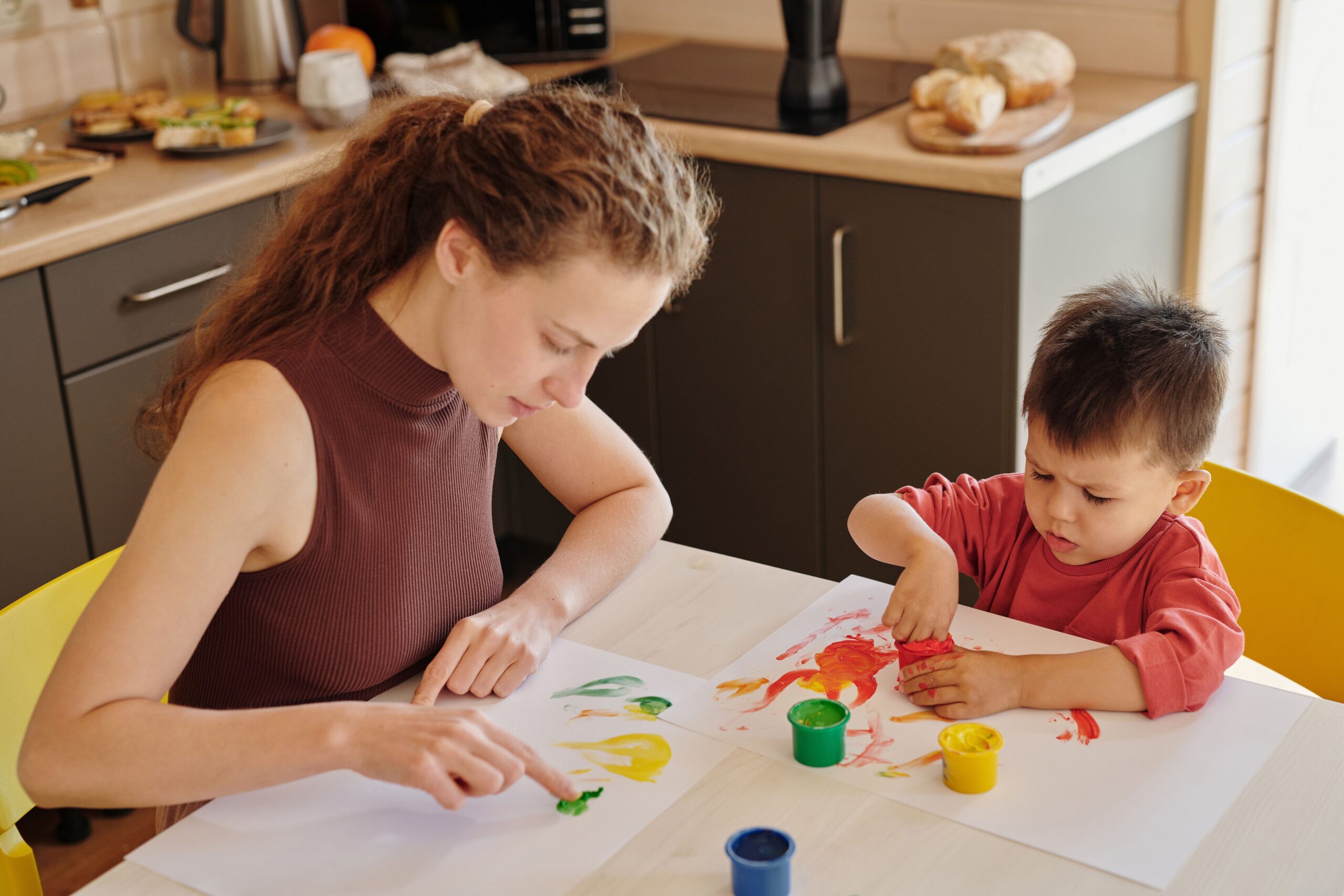 Art supplies for toddlers: a parent and child finger painting together at the table