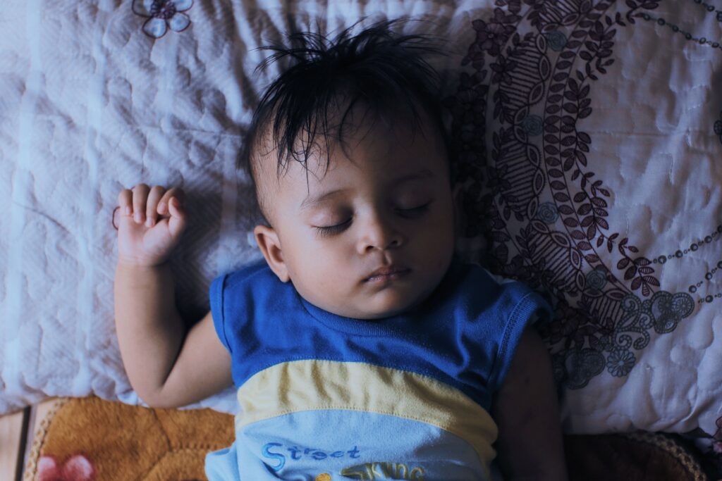 Baby sleeping in pajamas on bed, bamboo vs cotton fabric comparison