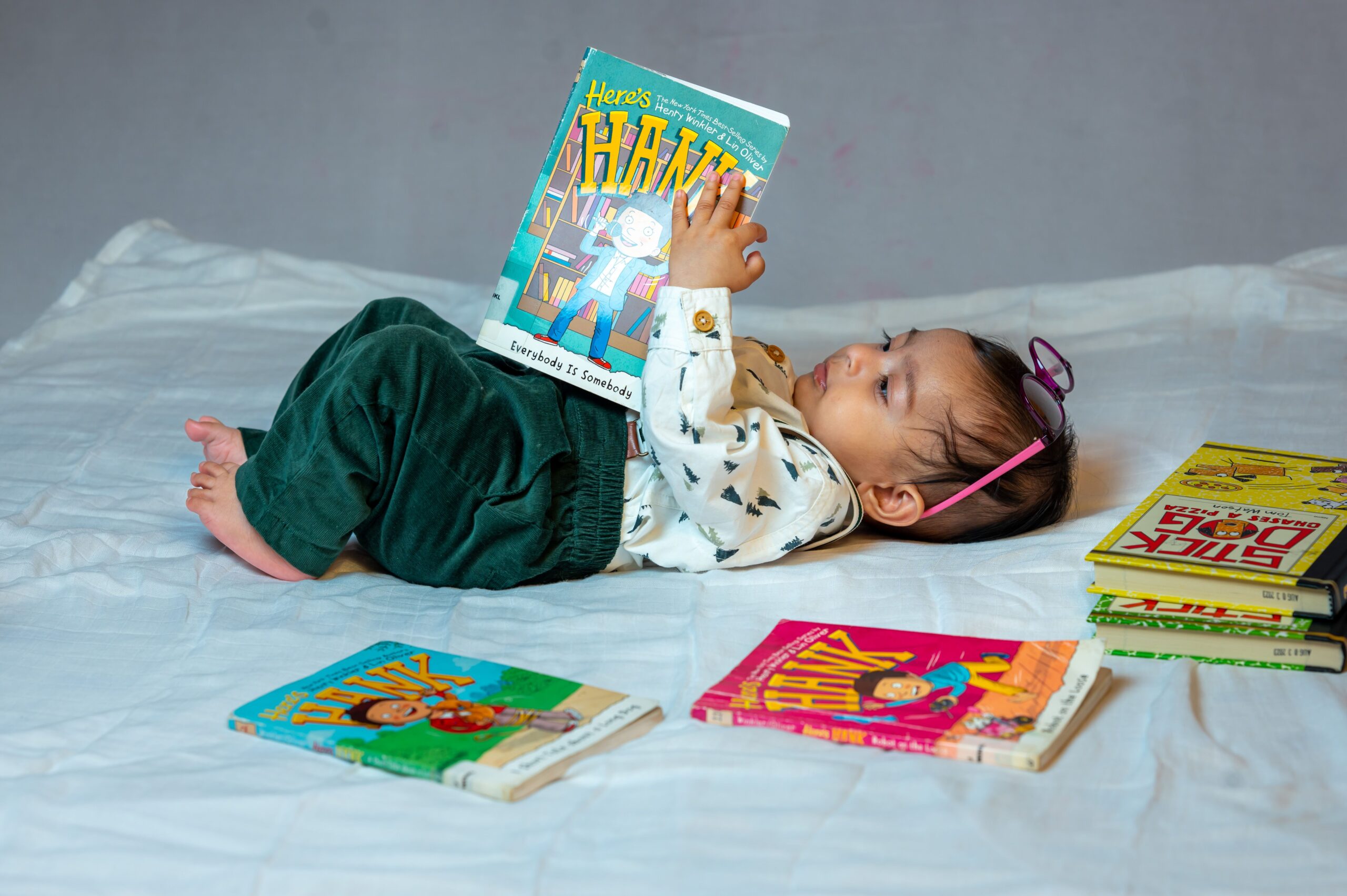Best board books for babies: a baby lying on a bed reading colorful board books