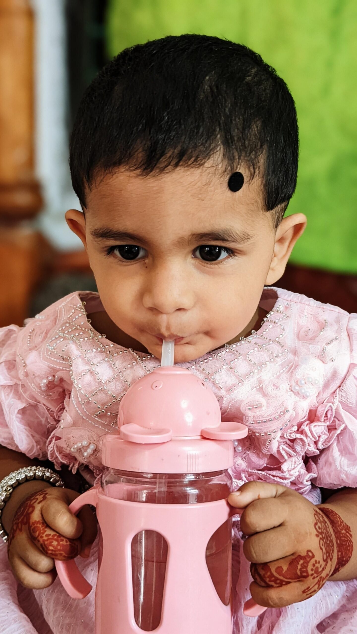 Best straw cups for toddlers: a baby drinking from a pink straw cup