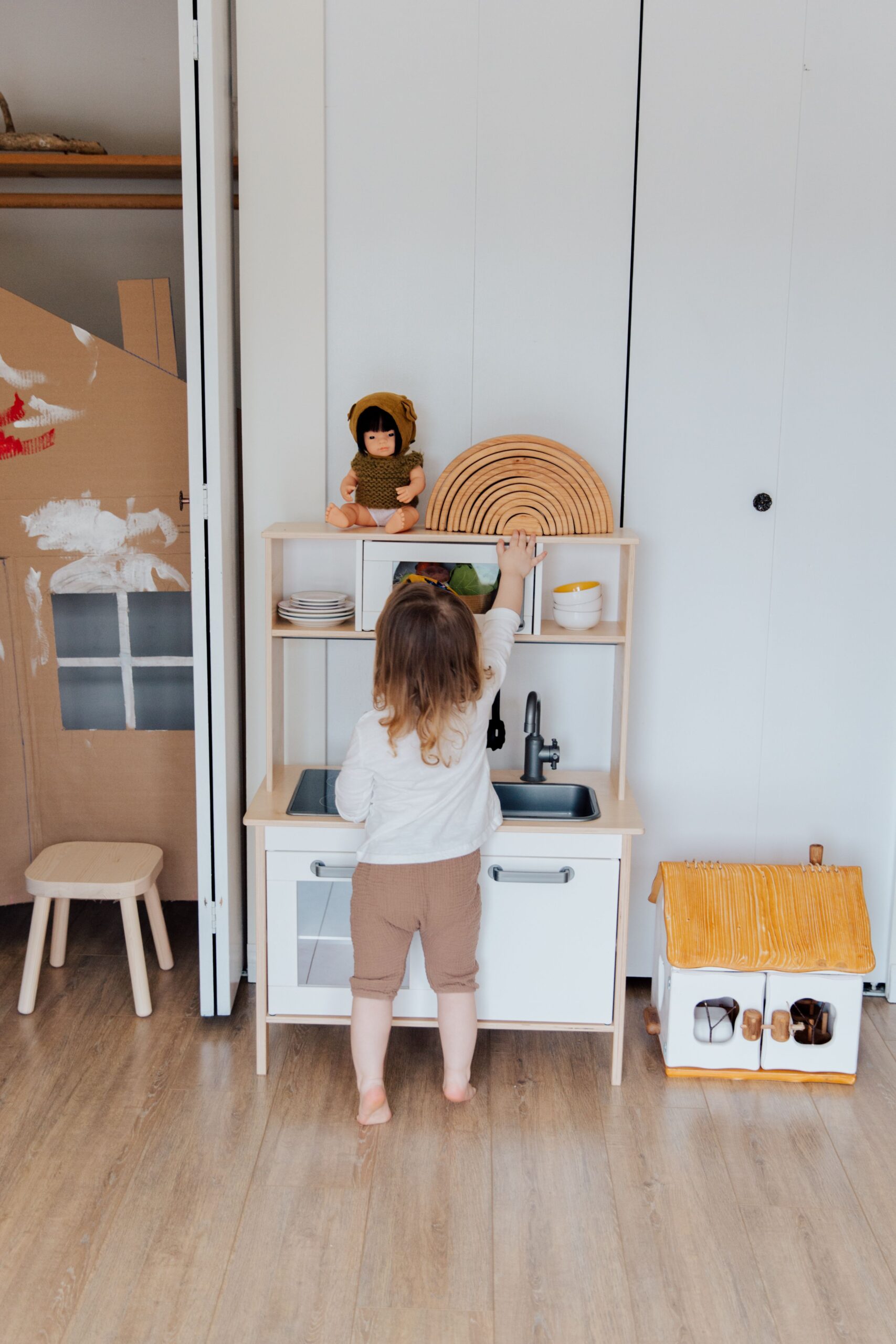 Montessori practical life toys for toddlers: a toddler playing with a toy kitchen