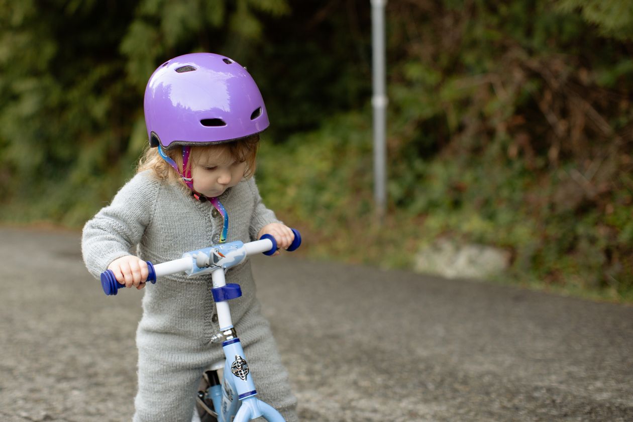 Toddler in a properly fitted helmet on a balance bike, whatever age they start riding