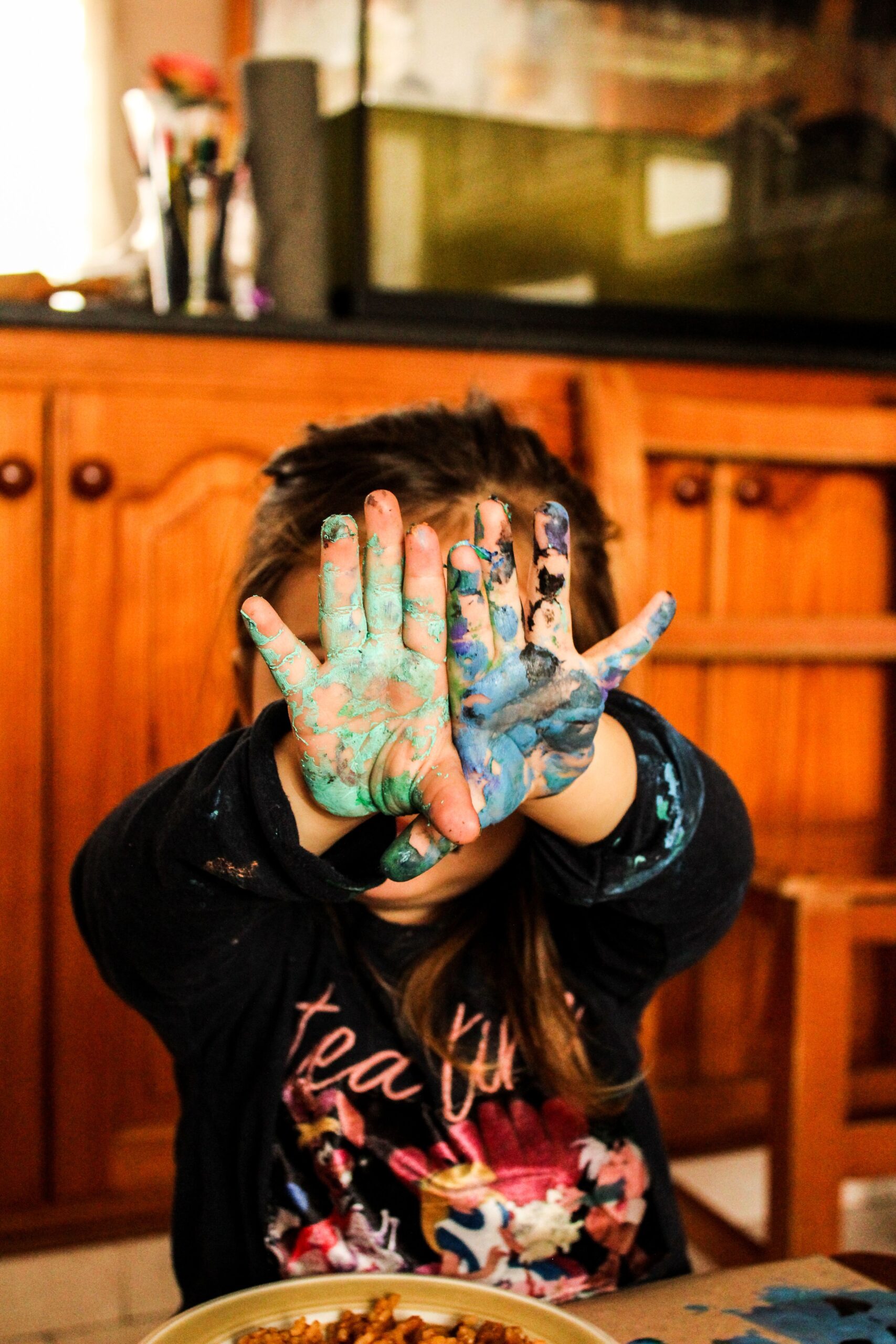 Toddler with colorful painted hands from a finger painting sensory activity