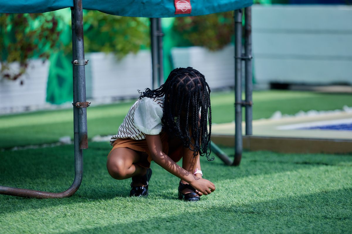 Trampoline for toddlers age 2-5: a child near a trampoline with a safety net enclosure in the yard