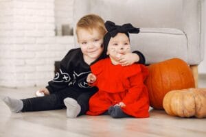 Two toddlers in halloween costumes sitting with pumpkins, a calm daycare-style setup for daycare halloween activities for toddlers