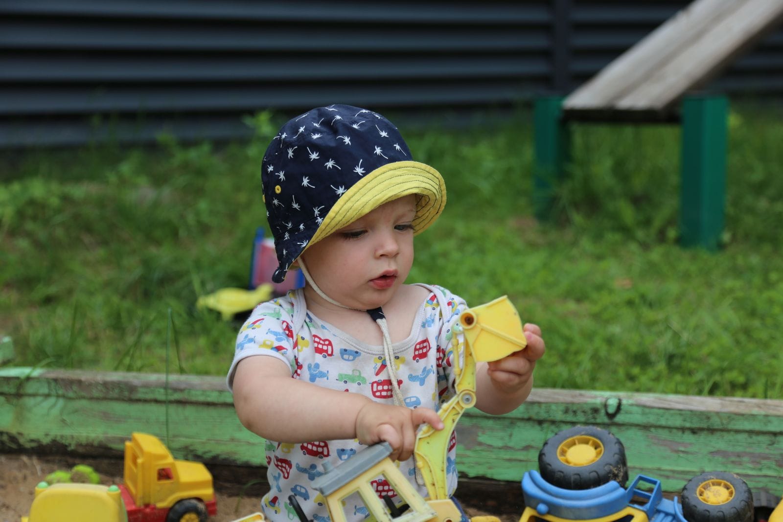 Toddler with toy construction pieces outdoors near a DIY kids playground build