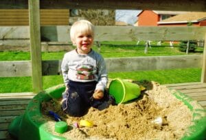 Toddler digging in a homemade DIY kids playground sandbox