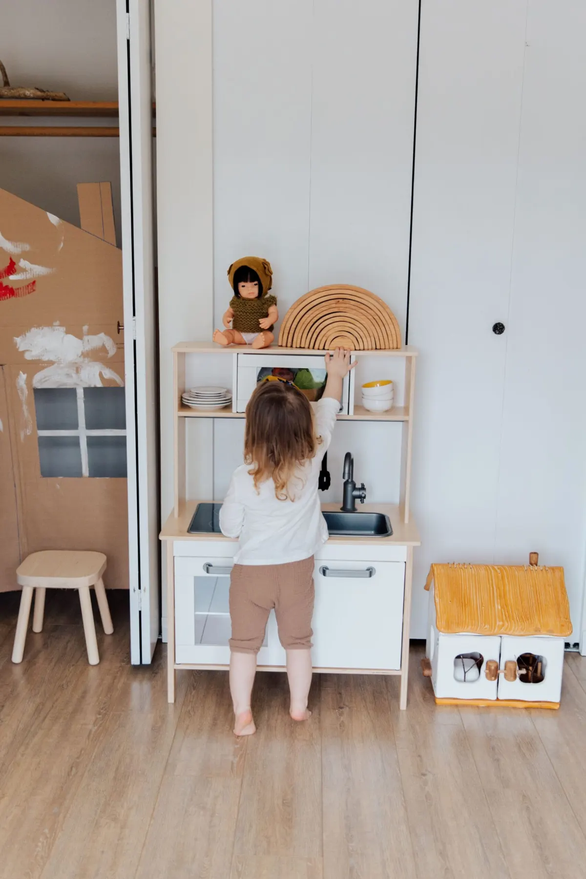 Montessori practical life toys for toddlers: a toddler playing with a toy kitchen