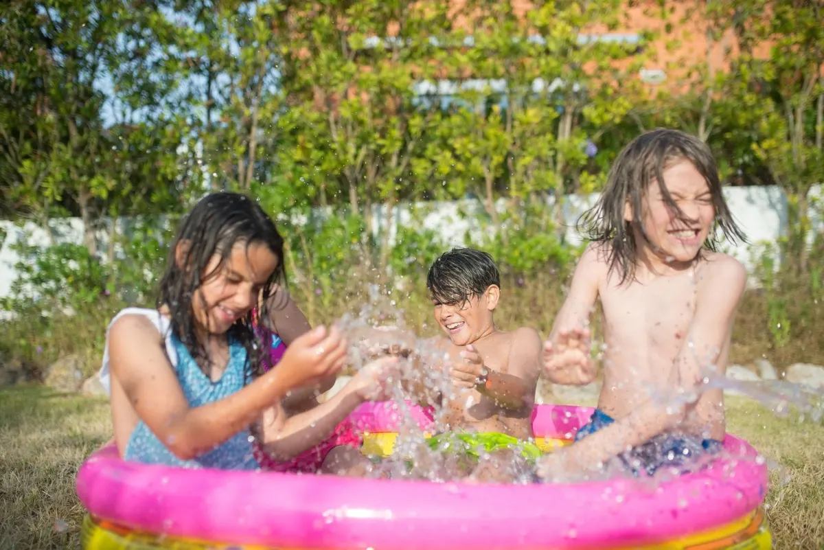 Kids splashing water outdoors, an example of outdoor activities for toddlers that use water play