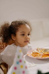 Toddler girl eating a plate of dairy free meals for toddlers 2 year old at a party table